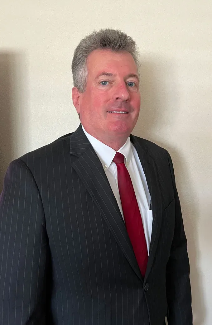 A man in a suit standing in front of a wall.